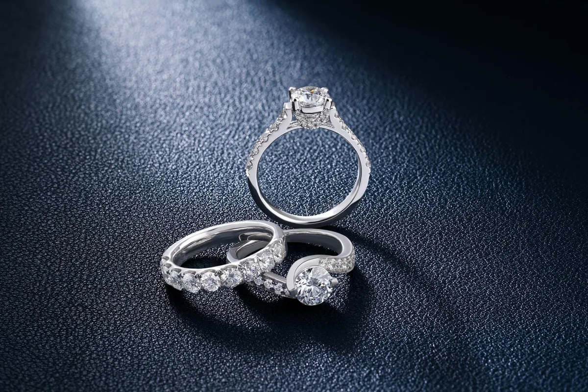 Close-up of luxurious diamond engagement and wedding rings on a textured surface, showcasing elegance and craftsmanship.